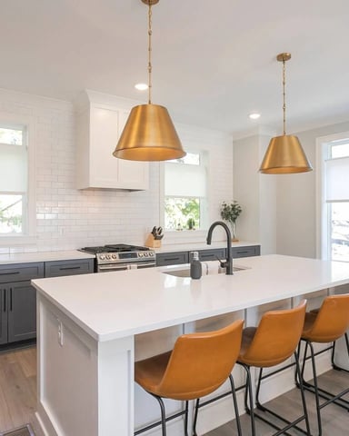 Bright kitchen with white subway tile, gold pendant lights, and island seating